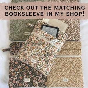 May include: A collection of quilted fabric pouches with floral patterns in olive, brown, black, and mustard yellow. Each pouch features a zip, a small label reading aster & lily, and text stating CHECK OUT THE MATCHING BOOKSLEEVE IN MY SHOP!