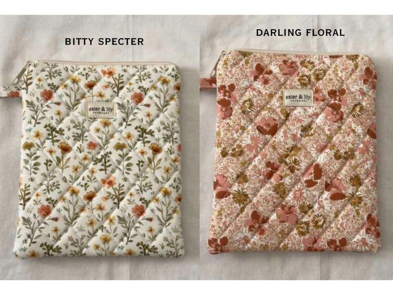 May include: Two rectangular quilted pouches with zips. The left pouch, labelled BITTY SPECTER, features a white fabric with a scattered orange and green floral print. The right pouch, labelled DARLING FLORAL, has a dense pink and brown floral pattern. Both have an aster & lily label.
