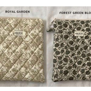 May include: Two rectangular quilted zip pouches featuring floral patterns. The left pouch is labelled ROYAL GARDEN with a beige floral print, and the right is labelled FOREST GREEN BLOOMS with a dark green floral print. Both have a small tag.