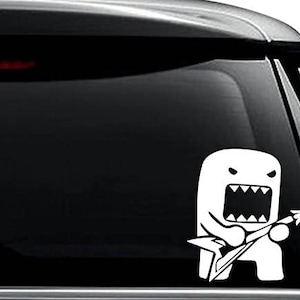 May include: White vinyl decal of a cartoon character with a wide-open mouth and jagged teeth, playing an electric guitar. The decal is affixed to the black window of a vehicle.