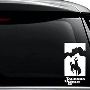 May include: White vinyl decal sticker with a silhouette of a cowboy riding a horse against a cloudy sky. The text "JACKSON HOLE" is below the silhouette.