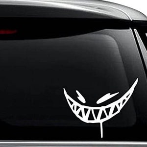 May include: White vinyl decal of a cartoonish, toothy grin with dripping saliva. The grin is on a black background, possibly a car window.