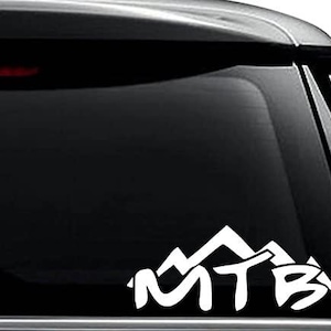 May include: White vinyl decal of a mountain range with the word "MTB" in a stylized font. The decal is on a black car window.