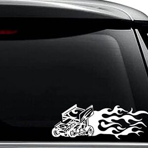 May include: White vinyl decal of a race car with flames coming out of the back. The car is stylized and has a tribal design.