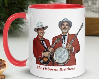 May include: White ceramic mug with a red rim and handle. The mug features a color image of two men in red suits playing musical instruments. The text "The Osborne Brothers" is printed in red at the bottom of the mug.