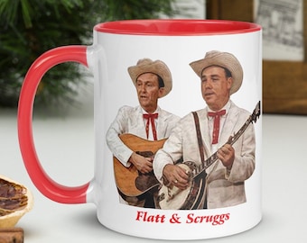 May include: White ceramic mug with a red rim and handle. The mug features a vintage image of musicians Flatt & Scruggs playing instruments. The text "Flatt & Scruggs" is printed in red at the bottom of the mug.