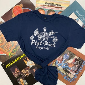 May include: A navy blue t-shirt with a white graphic of a band playing guitars. The graphic says "Flat Pick Legends".