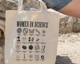May include: A beige tote bag with a black print of "Women in Science" and a list of women scientists with their names and years of birth. The list includes Marie Curie, Grace Hopper, Rosalind Franklin, and many more.