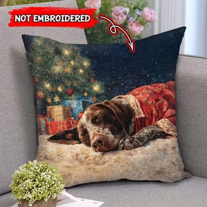 May include: Decorative square pillow featuring a sleeping brown and white dog wearing a red and floral patterned shirt. The pillow has a Christmas tree and wrapped gifts in the background. The text "NOT EMBROIDERED" is in the upper left corner.