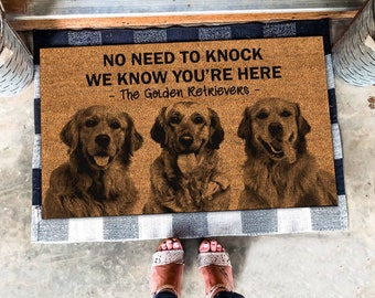 Puede incluir: Una alfombra de coco marrón con el texto "NO NEED TO KNOCK WE KNOW YOU'RE HERE - The Golden Retrievers -" y una foto de tres golden retrievers.
