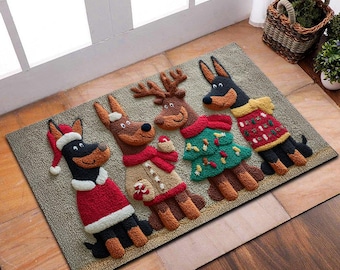 Op de afbeelding: Een rechthoekige deurmat met vier honden in feestelijke kleding. Eén hond draagt een kerstmuts en een rode trui, een andere een rendierkostuum, een derde een kerstboomoutfit en de laatste een rode trui. De mat is beige.