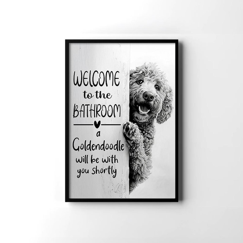 以下が含まれることがあります： 「WELCOME to the BATHROOM a Goldendoodle will be with you shortly」のテキストが入った黒いフレームのウォールアート。壁の後ろから覗いているゴールデン・ドゥードゥルの白黒画像。