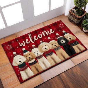 May include: A rectangular red doormat with a plaid pattern and the word "welcome" in white script. The mat features illustrations of six dogs wearing sweaters and winter hats. Snowflakes are scattered across the surface.
