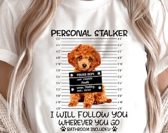 May include: A white t-shirt with a brown poodle dog wearing a police mugshot sign that says "Police Dept. Code #180326781 Poodle Crime: Stalking. Date: 13/10". The text on the shirt says "Personal Stalker I Will Follow You Wherever You Go Bathroom Included".