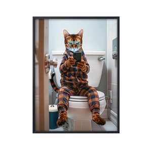May include: A cat wearing pajamas sits on a toilet and looks at a smartphone. The cat is wearing a plaid shirt and pants. The toilet is white and has a closed lid. The bathroom is white with a white door in the background.