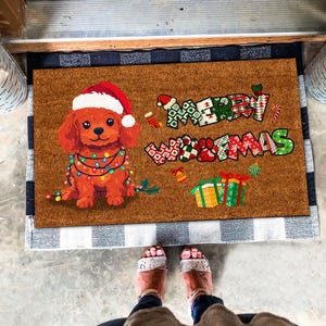 May include: A brown doormat with a red and white Christmas themed design. The design features a dog wearing a Santa hat and a string of lights. The text "Merry Christmas" is written in a festive font.