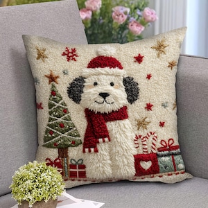 Op de afbeelding: Een decoratief kerstkussen met een witte hond met een rode sjaal en muts. Het kussen heeft een kerstboom, cadeaus en steraccenten. Het kussen is vierkant en gemaakt van een textuurstof.