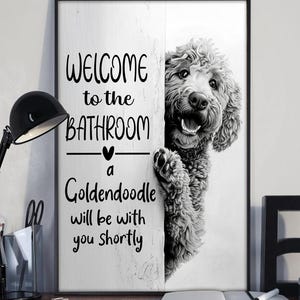 以下が含まれることがあります： 「WELCOME to the BATHROOM a Goldendoodle will be with you shortly」のテキストと、壁の後ろから覗くゴールデン・ドゥードルのグレースケール画像が特徴の、黒いフレームのウォールアート。
