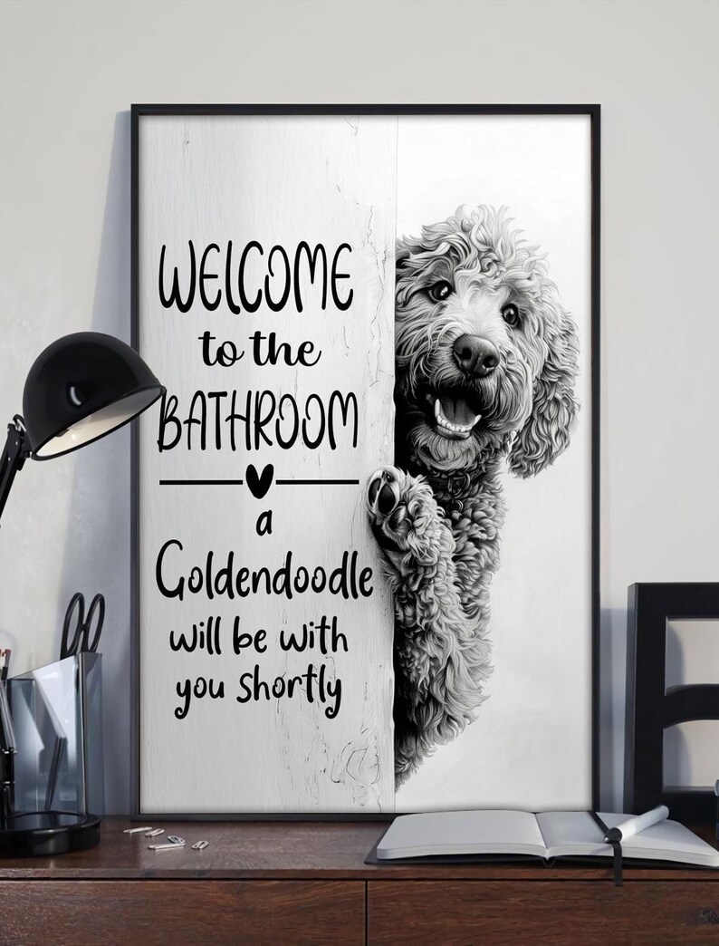 以下が含まれることがあります： 「WELCOME to the BATHROOM a Goldendoodle will be with you shortly」のテキストと、壁の後ろから覗くゴールデン・ドゥードルのグレースケール画像が特徴の、黒いフレームのウォールアート。