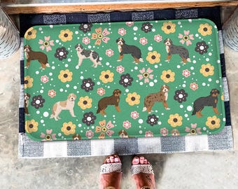 May include: Green doormat with a repeating pattern of white flowers, brown dots, and black and white dogs. The dogs are in various poses, including sitting, standing, and running.
