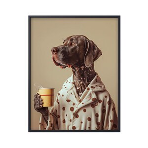 May include: A brown and white dog wearing a white polka dot robe holds a yellow mug with a red stripe. The dog is looking to the left of the frame.