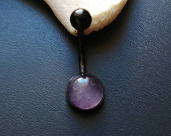 Peut inclure: Un piercing de nombril noir avec une pierre précieuse violette.