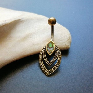 Puede incluir: Anillo de ombligo dorado con un colgante de hoja adornado de tres capas, con una concha de abulón iridiscente.