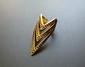 Puede incluir: Anillo de metal dorado con un diseño geométrico que presenta tres triángulos superpuestos. El anillo es abierto y ajustable.