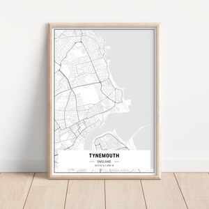 May include: A black and white map print of Tynemouth, England. The map shows the streets and coastline of the town. The print is framed in a light wood frame.