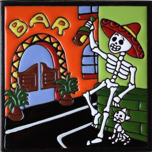May include: A colorful ceramic tile with a skeleton wearing a sombrero and holding a bottle of alcohol. The skeleton is standing in front of a building with a sign that says "BAR".