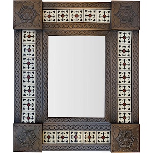 Op de afbeelding: Rechthoekige spiegel met een decoratief frame. Het donkerbruine frame heeft een herhalend golvend patroon en vierkante tegels met rode en zwarte kruisontwerpen. De hoeken hebben reliëf bloemmotieven.