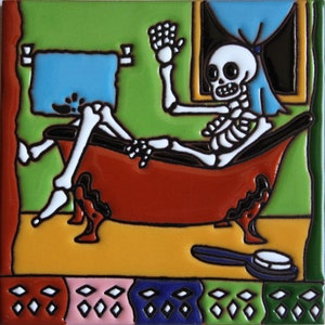 May include: A colorful ceramic tile depicting a skeleton in a bathtub with a blue towel hanging on the wall behind it. The skeleton is waving with one hand and has a toothbrush on the floor next to the tub.