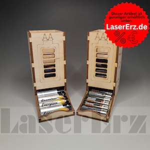 Könnte beinhalten: Zwei hölzerne Batterie-Organizer mit einer Schublade zum Aufbewahren von AA-Batterien. Die Organizer sind mit "AA" beschriftet und haben ein Batterie-Symbol. Der Text "LaserErz.de" befindet sich auf der rechten Seite des Bildes.