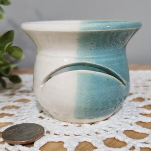 May include: A white ceramic mug with a black handle and the text "But First, Coffee" in a handwritten style. The mug is on a white surface. The mug is approximately 4 inches tall.