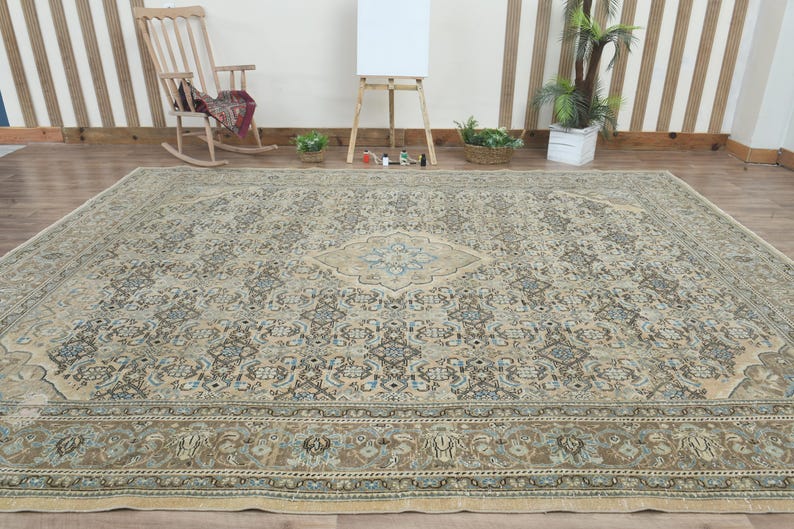 May include: Large, rectangular area rug with an intricate, traditional design. The rug features a central medallion and border in shades of beige, blue, and brown. The rug is placed on a wooden floor.