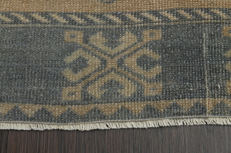 May include: Close-up of a rug with a blue and beige geometric pattern. The rug has a fringed border.