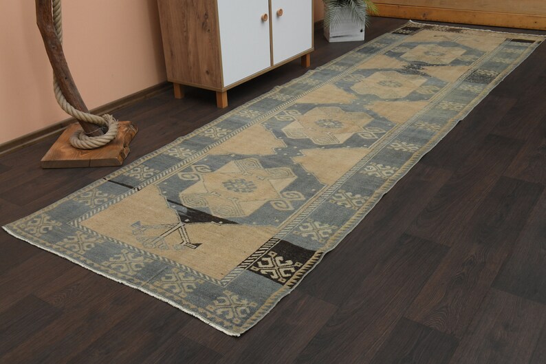 May include: A blue and beige runner rug with a geometric pattern. The rug has a distressed look and is made of wool.
