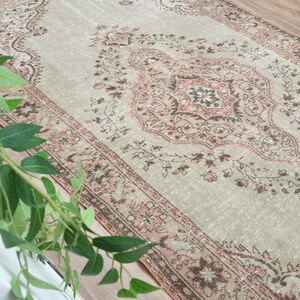 Puede incluir: Una alfombra vintage con fondo gris claro y un patr&oacute;n floral rosa y marr&oacute;n. La alfombra tiene un aspecto desgastado y es perfecta para a&ntilde;adir un toque de estilo bohemio a tu hogar.