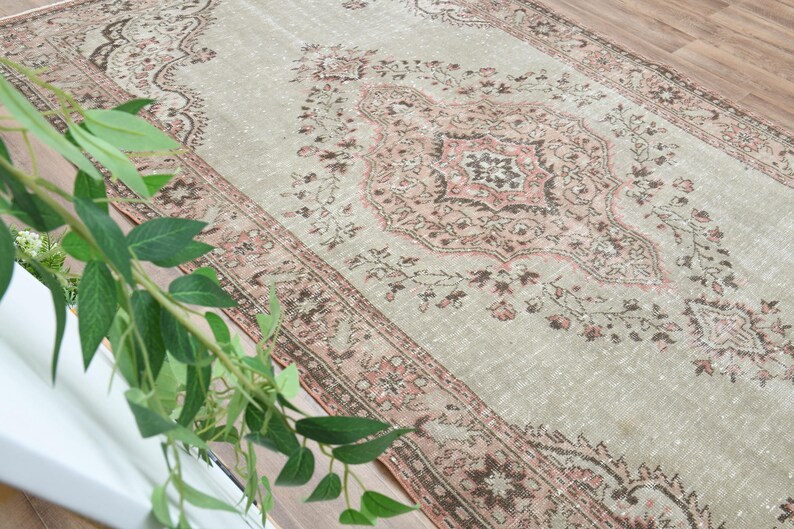 Puede incluir: Una alfombra vintage con fondo gris claro y un patr&oacute;n floral rosa y marr&oacute;n. La alfombra tiene un aspecto desgastado y es perfecta para a&ntilde;adir un toque de estilo bohemio a tu hogar.