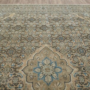 May include: A large, rectangular area rug with an intricate, traditional design. The rug features a central medallion and a border with repeating patterns in shades of beige, brown, and blue. The rug is made of a soft material.