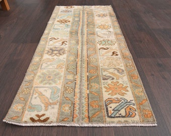 May include: A vintage runner rug with a cream background and intricate floral patterns in shades of beige, brown, and blue. The rug has a fringed edge.