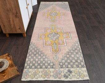 Puede incluir: Un corredor de pasillo rosa y amarillo con un diseño geométrico. La alfombra tiene un aspecto descolorido y vintage, perfecto para añadir un toque de estilo bohemio a cualquier habitación.