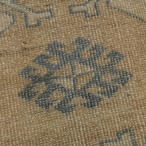 May include: Close-up of a woven rug with a geometric pattern in shades of brown and blue.