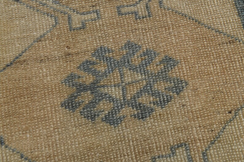May include: Close-up of a woven rug with a geometric pattern in shades of brown and blue.