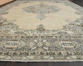 Puede incluir: Una alfombra rectangular grande con un diseño tradicional intrincado. La alfombra presenta un campo central de color crema con un medallón detallado de inspiración floral. El borde y los acentos son en tonos de marrón y gris, creando una estética vintage.