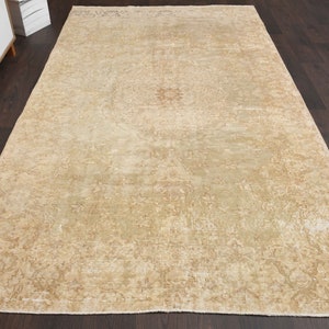 May include: A vintage rug with a faded floral pattern in shades of beige and cream. The rug has a distressed look and is made of natural fibers.