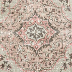 Puede incluir: Una alfombra vintage con un esquema de color rosa y beige descolorido. La alfombra presenta un medall&oacute;n central con intrincados patrones florales y un dise&ntilde;o geom&eacute;trico repetitivo.