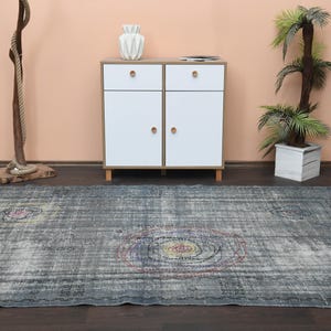 May include: A gray and blue vintage rug with a faded floral pattern. The rug has a distressed look and is perfect for adding a touch of bohemian style to any room.