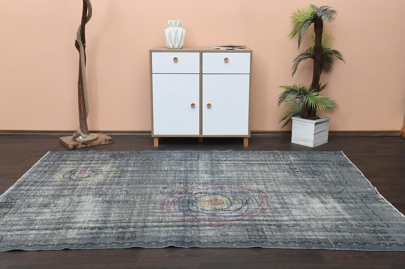 May include: A gray and blue vintage rug with a faded floral pattern. The rug has a distressed look and is perfect for adding a touch of bohemian style to any room.