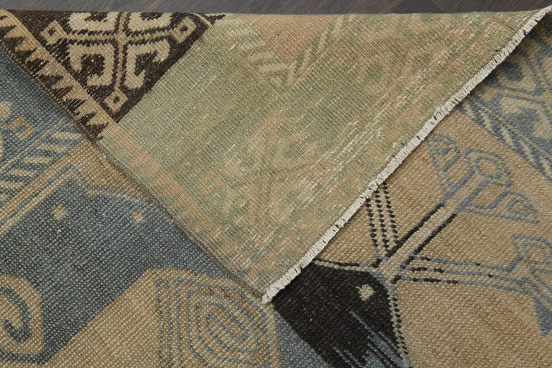 May include: Close-up of a multi-coloured woven rug with a geometric pattern. The rug has a fringed border and is made of natural fibres.